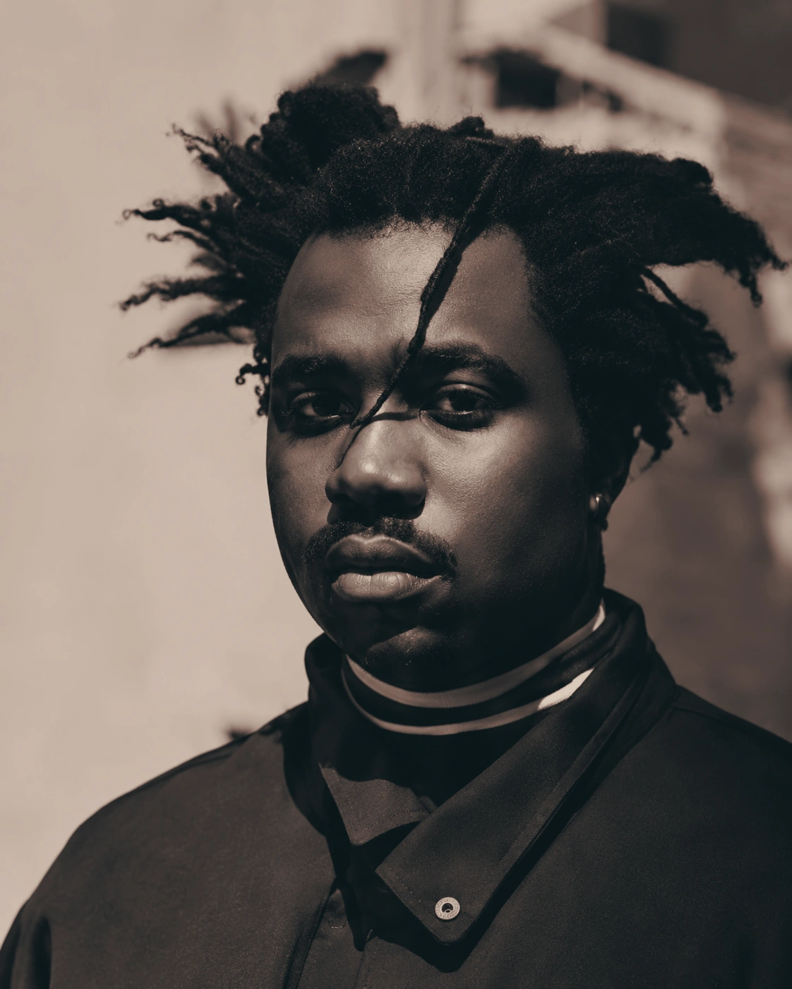 Editorial portrait of a man with short dreadlocks